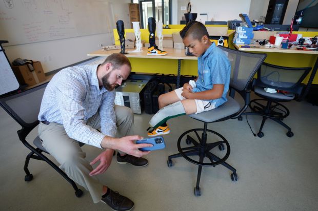 A man shows a boy an app used to scan his missing leg.