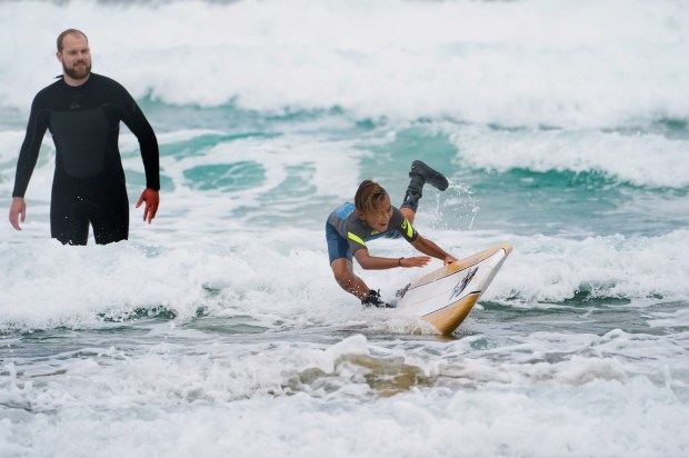 A boy with a prosthetic limb wipes out while surfing.