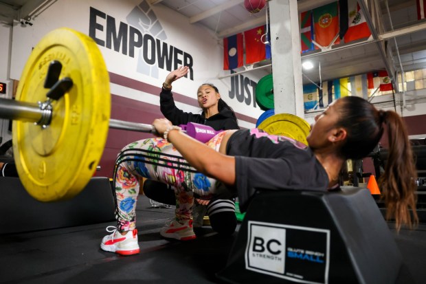 Coach and owner Jennifer Hernando, left, directs Rachel Elumba, of Vallejo, as she works her body with barbell hip thrust repetitions during a fitness class at Hernando's gym, Jenuine Fitness, in San Pablo, Calif., on Tuesday, May 7, 2024. Hernando is celebrating five years since her gym was founded. (Ray Chavez/Bay Area News Group)