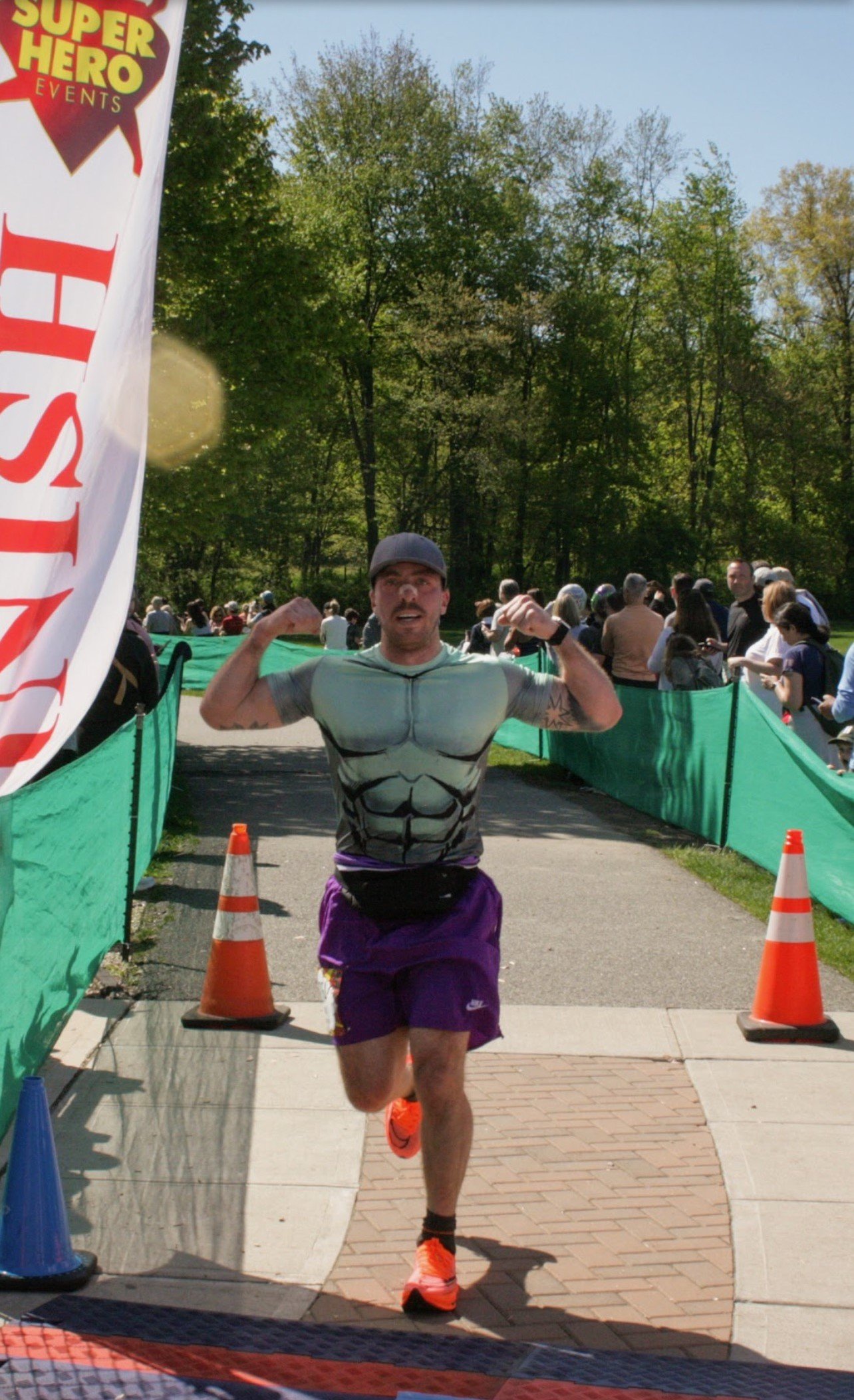 Marc Guido running across the finish line in a Hulk t-shirt