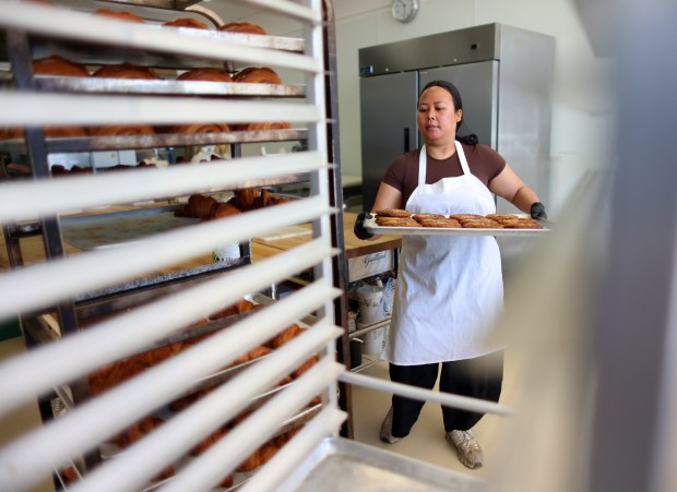 East Bay Bakery owner Gabriela Lubaba carries a tray of chocolate chip cookies on Thursday, April 18, 2024, in Danville, Calif. The cookies are made with dark chocolate chips along with Valrhoan Blond Dulcey chocolate chips and sprinkled with Maldon sea salt. (Aric Crabb/Bay Area News Group)