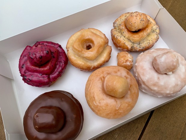 Founders Donuts sampler box includes, clockwise from top left, blueberry, signature vanilla and lemon-poppy seed old-fashioned doughnuts and coconut, glazed and bittersweet chocolate milk bread doughnuts. (Jackie Burrell/Bay Area News Group)