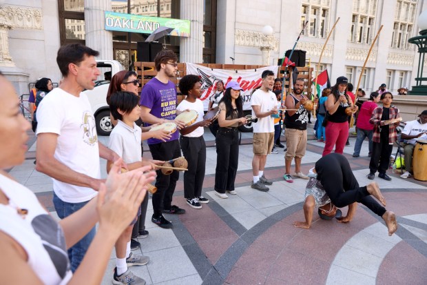 Pro-Palestinian protesters gather as a man break dances at a May Day rally at City Hall in downtown Oakland, Calif., on Wednesday, May 1, 2024. Multiple protests took place throughout the Bay Area as part of May Day action in support of workers and Palestinian people. (Jane Tyska/Bay Area News Group)