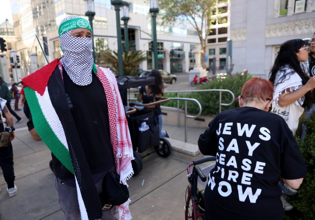 Chris Khamis, of Hayward, gathers with other pro-Palestinian protesters at a May Day rally at City Hall in downtown Oakland, Calif., on Wednesday, May 1, 2024. His mom who was born in Palestine knitted the flag he's carrying. Multiple protests took place throughout the Bay Area as part of May Day action in support of workers and Palestinian people. (Jane Tyska/Bay Area News Group)