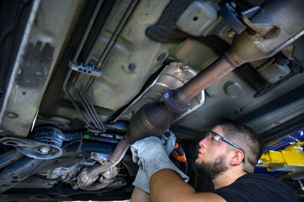 ExperTec Automotive technician Juan Martinez etches a catalytic converter with the car's license plate number in Huntington Beach on Saturday, November 13, 2021. The free public service, sponsored by local police departments, aimed to deter thefts. Converters are increasingly being stolen for the precious metals they contain. (Photo by Mindy Schauer, Orange County Register/SCNG)