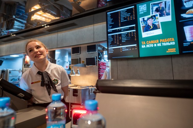 A staff member speaks with visitors at a newly opened fast food restaurant in a former McDonald's outlet in Bolshaya Bronnaya Street in Moscow, Russia, Sunday, June 12, 2022. The first of former McDonald's restaurants is reopened with new branding in Moscow. The corporation sold its branches in Russia to one of its local licensees after Russia sent tens of thousands of troops into Ukraine. (AP Photo/Dmitry Serebryakov)