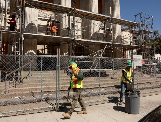 Crews from Garden City Construction sweep up the plastic littering Saint James Street from the degraded protective covering at the historic First Church of Christ, Scientist building in San Jose, Calif., Tuesday, August 29, 2023. (Karl Mondon/Bay Area News Group)