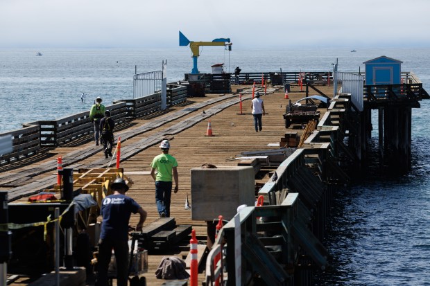 Construction crew continue to rebuild the damaged Capitola Wharf in Capitola, Calif., on Friday, May 17, 2024. The Capitola Wharf, an 855-foot-long landmark that has delighted generations of beach visitors since its construction in 1857, was badly damaged in winter storms last year. (Dai Sugano/Bay Area News Group)