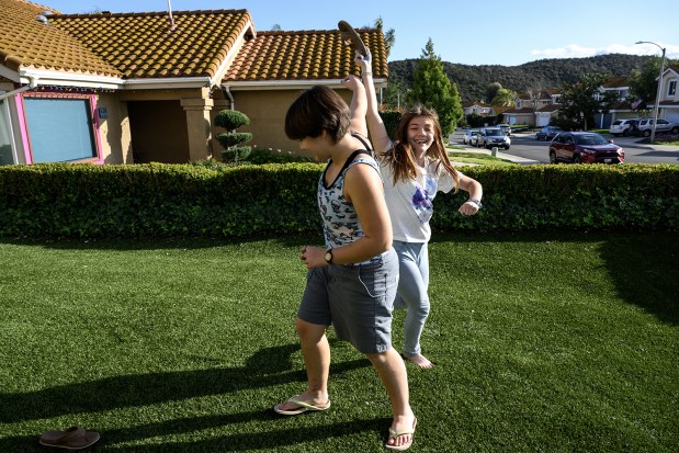 Siblings Kestrel Wineman, 13, left, and Rosie Wineman, 11, goof around in their front yard in Murrieta. Kestrel is nonbinary and prefers the pronouns they/them. (Gina Ferazzi/Los Angeles Times/TNS)